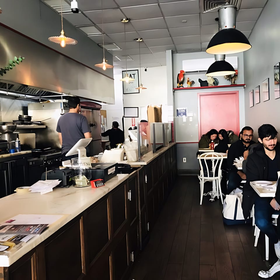 A busy Roast & Co. restaurant interior with staff working and customers dining at tables.