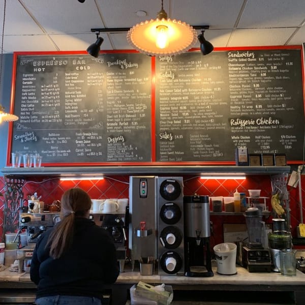 A customer stands at the counter of Roast & Co, with a large menu board above.