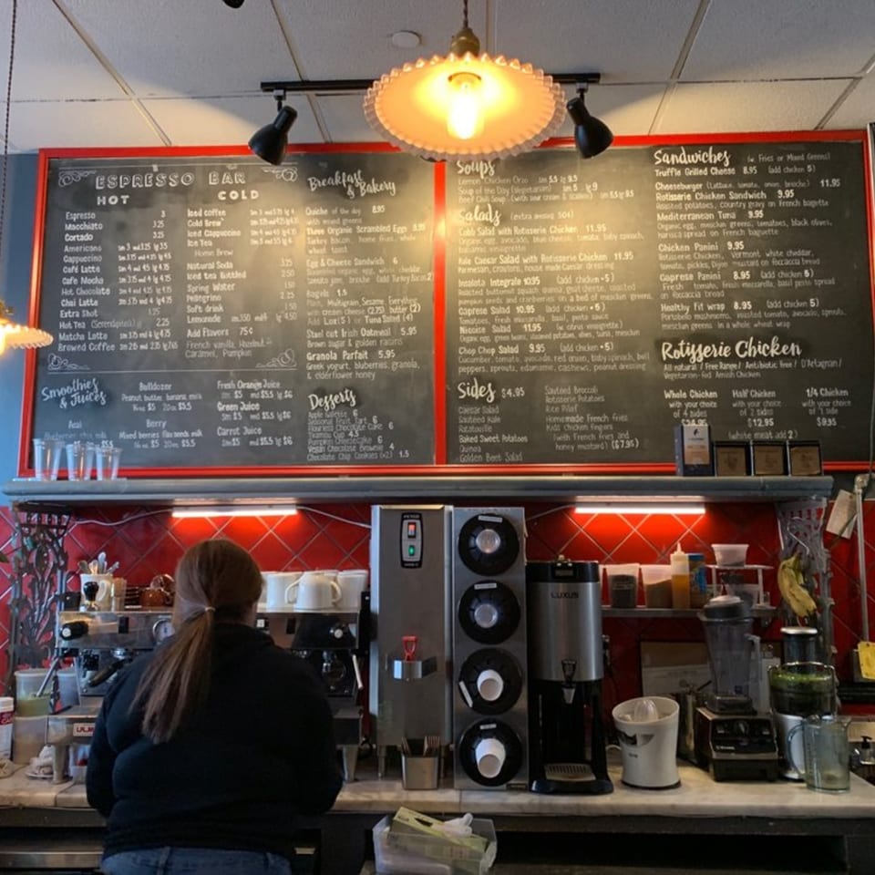 A customer stands at the counter of Roast & Co, with a large menu board above.