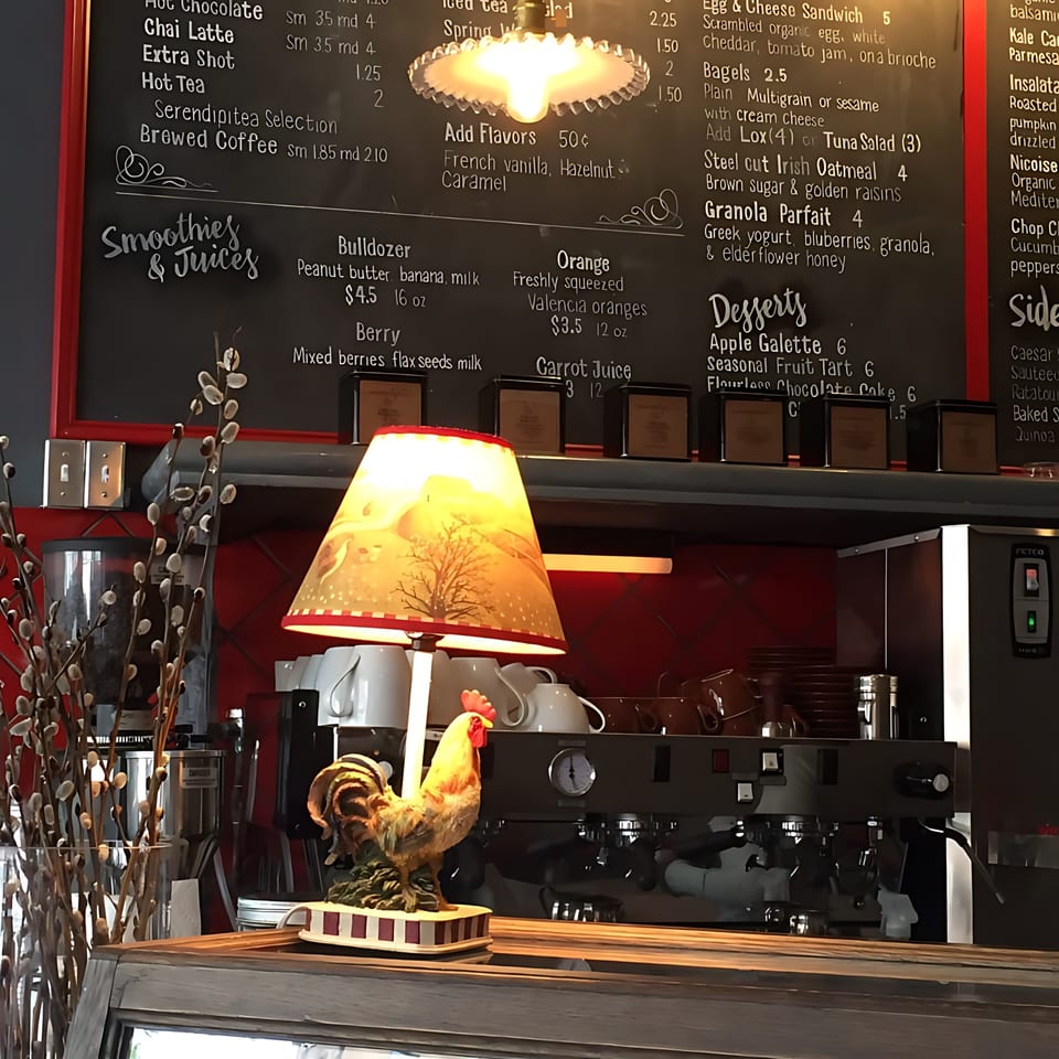 A rooster figurine and a lamp on a counter with a menu board in the background at Roast & Co.