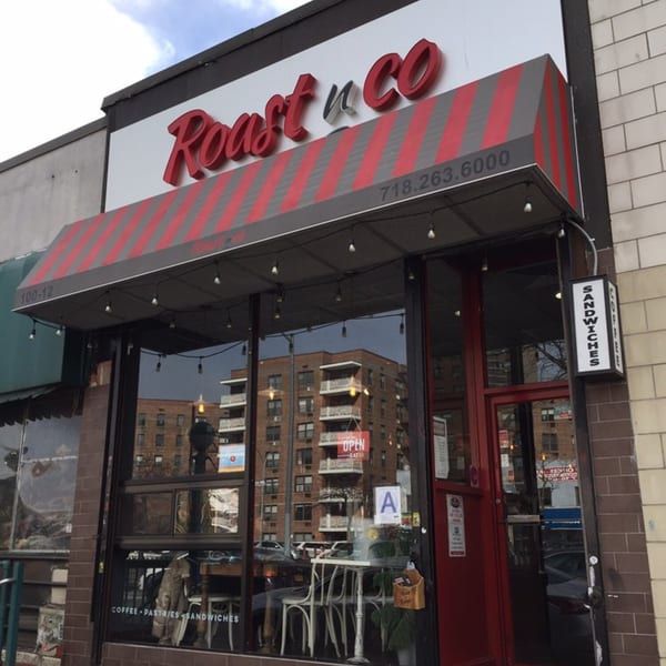 Exterior of Roast & Co, with a red and grey striped awning and large glass windows.