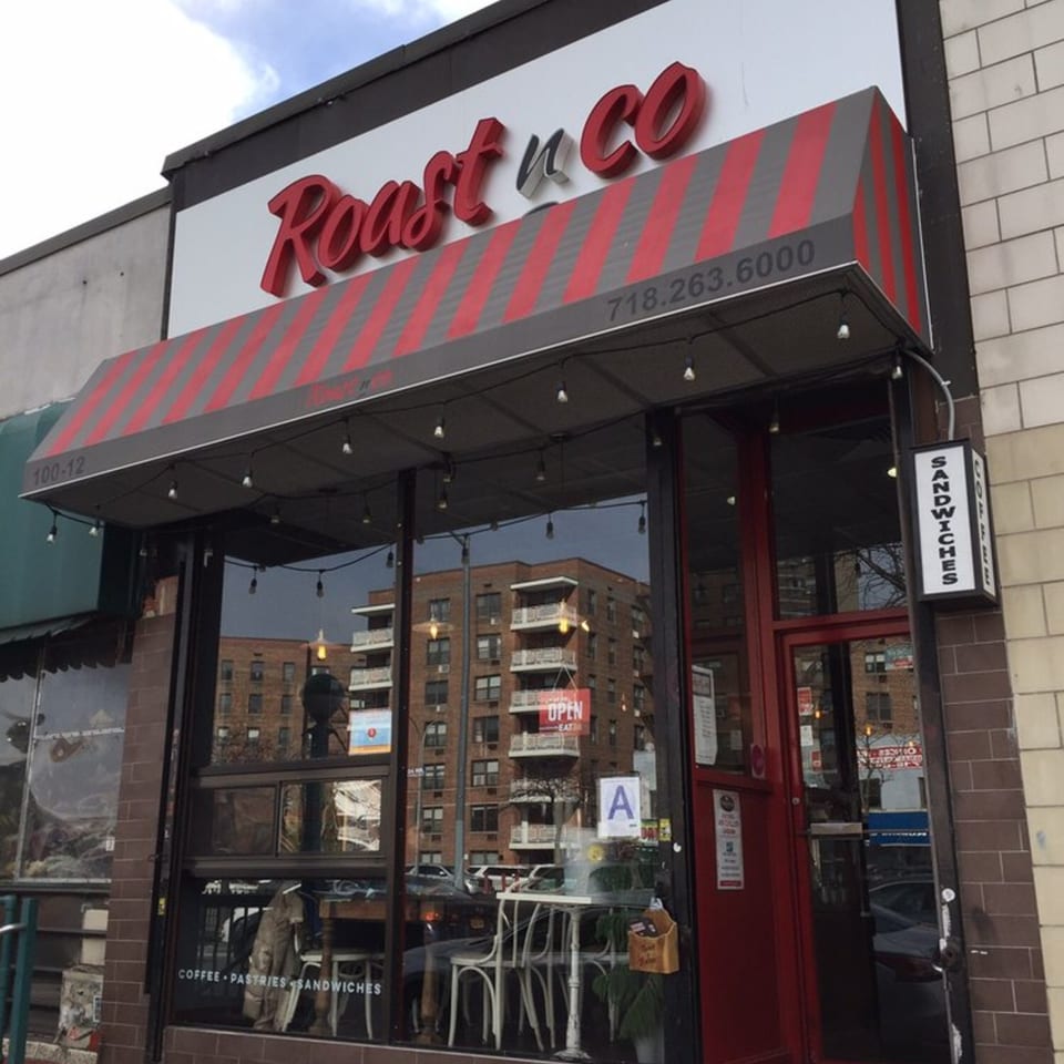 Exterior of Roast & Co, with a red and grey striped awning and large glass windows.