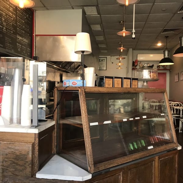 Interior of Roast & Co. with a wooden display case, menu board, and industrial lighting.