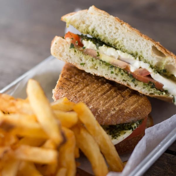 A Roast & Co. panini with pesto, mozzarella, and tomato, served with golden french fries.