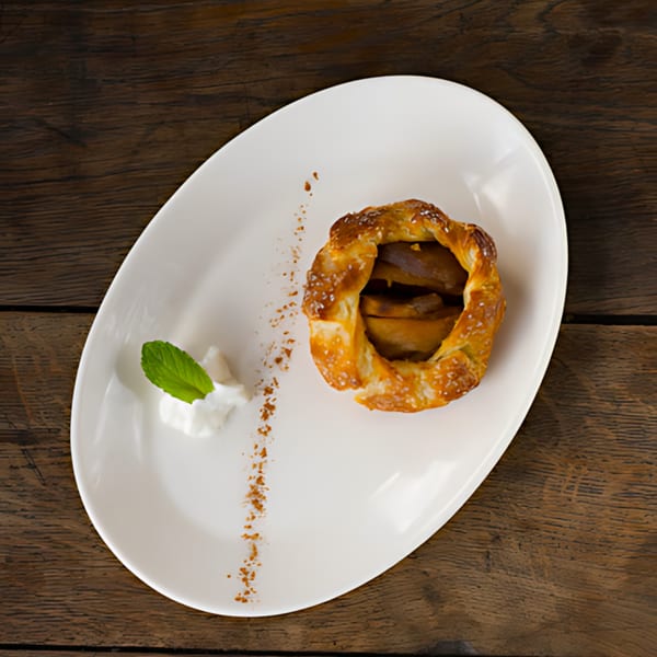 Roast & Co. apple tart with mint and cream on a white oval plate.